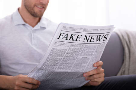 Close-up Of A Man's Hand Holding Newspaper With Fake News