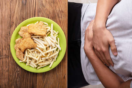 Unhealthy Food On Plate In Front Of Person Having Stomach Pain