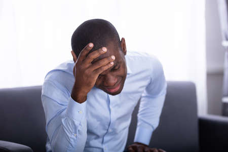 Close-up Of A Young African Man In Pain Holding His Headの写真素材