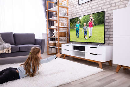 Girl Lying On Carpet Watching Television At Home