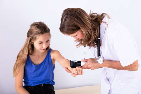 Female Doctor Examining Skin Of Girl With Dermatoscope In Clinicの写真素材
