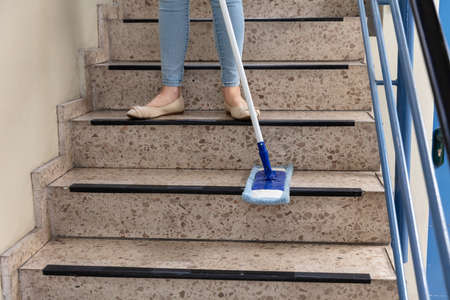 Young Female Janitor Cleaning Staircase With Mopの写真素材