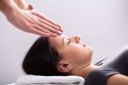 Close-up Of A Therapist Hand Giving Reiki Healing Treatment To Woman In Spa
