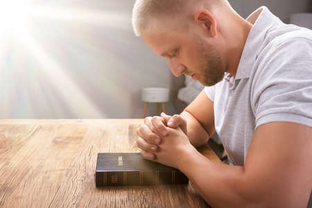 Sunlight Falling On Hand Over Bible While Praying