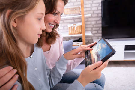 Close-up Of Happy Mother With Her Daughter Watching Video On Digital Tablet