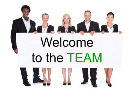 Group Of Smiling Businesspeople Holding Welcome To The Team Placard On White Background