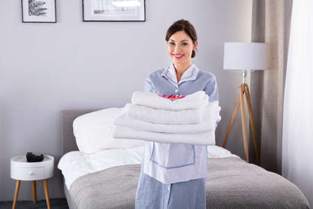 Portrait Of A Happy Young Woman With Stack Of White Towels