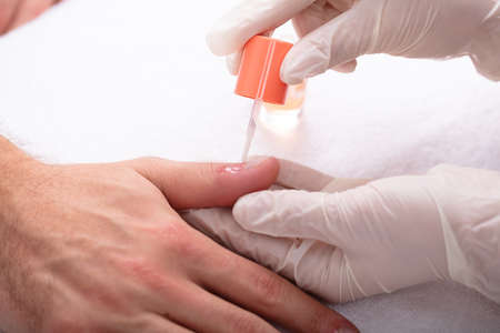 Close-up Of Beautician Applying Nail Oil On Man's Hand In Spaの写真素材