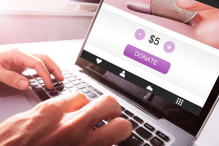 Close-up Of A Man's Hand Using Laptop To Donate Moneyの写真素材