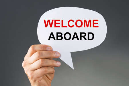 A Person's Hand Holding Welcome Aboard Thought Bubble On Grey Backgroundの写真素材