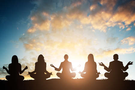 Silhouette Of People Doing Yoga Against Sky During Early Morningの写真素材
