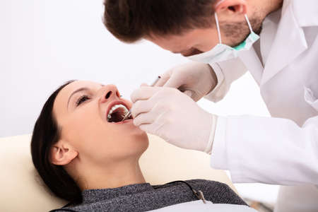 Close-up Of Dentist Examining Young Woman's Teeth In Clinicの写真素材