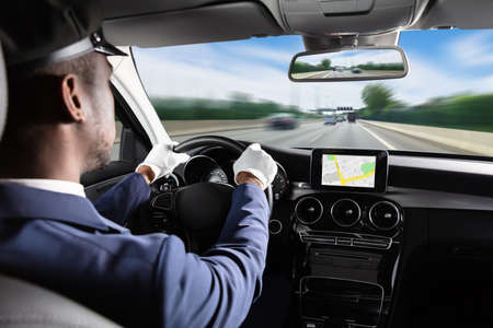 Male Chauffeur Using GPS Navigation Driving Car