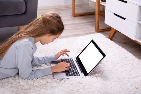 Side View Of A Girl Using Laptop With Blank White Screen