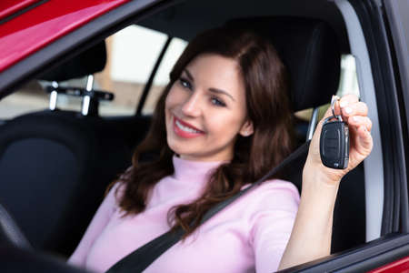 Close-up Of A Happy Young Woman Sitting Inside Car Showing Keyの写真素材