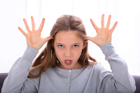 Girl Sticking Out Tongue While Making Teasing Faceの写真素材