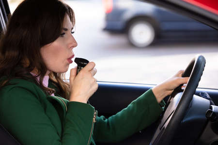 Side View Of A Beautiful Young Woman Sitting Inside Car Taking Alcohol Test