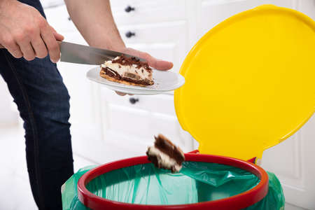 Close-up Of A Man Hand Throwing Cake In Trash Binの写真素材