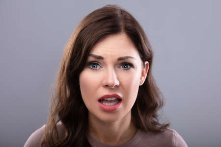 Portrait Of A Sad Young Woman On Grey Backgroundの写真素材