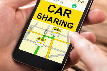 Close-up Of A Person's Hand Using Car Sharing Application On Mobile Phoneの写真素材