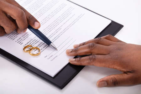 Judge Assisting Client In Filling Contract Form With Pair Of Golden Ringsの写真素材