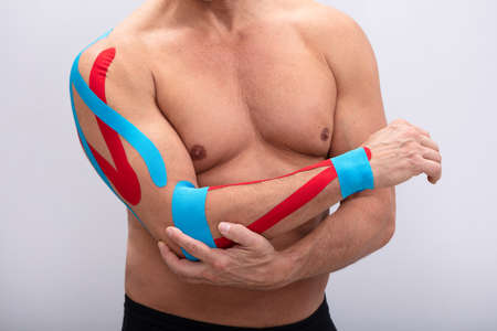 Mid-section  Man With Physio Tape On His Hand Against White Background. Body shape was altered...