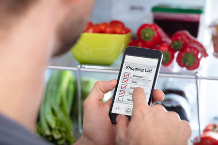 Close-up Of A Man Marking Shopping List On Mobile Phoneの写真素材