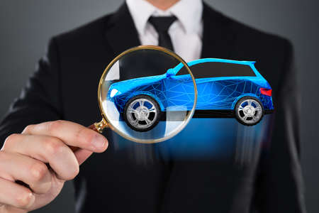 Blue Car With Polygonal Pattern Seen Through Businessperson Holding Magnifying Glassの写真素材
