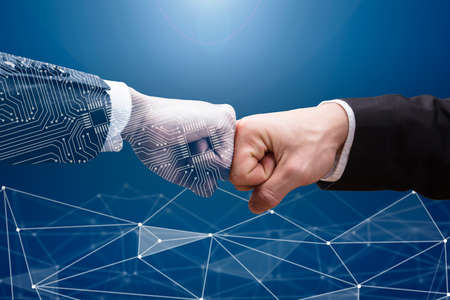 Close-up Of Digital Generated Human Hand And Businessman Making Fist Bump On Grey Background