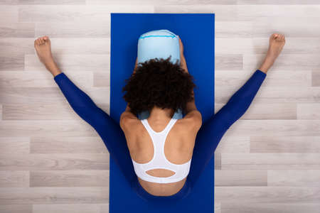 An Overhead View Of A Young Woman Sitting On Blue Exercise Mat Doing Yoga