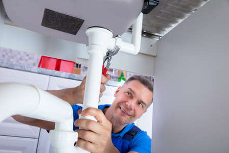 Front View Of Male Plumber Repairing Sink Pipe With Adjustable Wrench