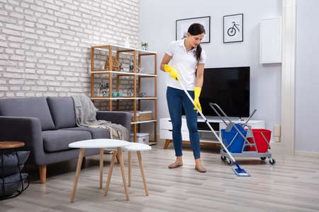 Female Janitor Cleaning Floor With Mop In Living Roomの写真素材