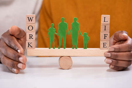 Person Protecting Work And Life Balance With Family Figures Standing Between Them On Seesaw