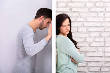 Side View Of Young Unhappy Couple Standing Back To Back At Home