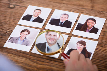 Businessperson Looking At Candidate's Photograph Through Magnifying Glassの写真素材