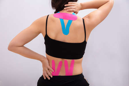 Woman Sitting With Physio Tape Applied On Her Back