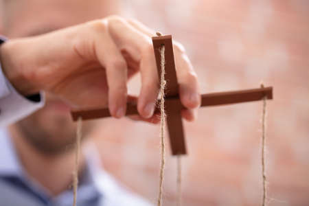 Close-up Of A Businessperson's Hand Manipulating Marionette With A Stringの写真素材