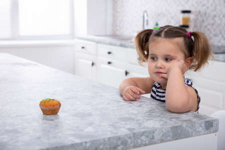 Close-up Of Girl Looking At Cupcake On Kitchen Worktopの素材 [FY310118828794]