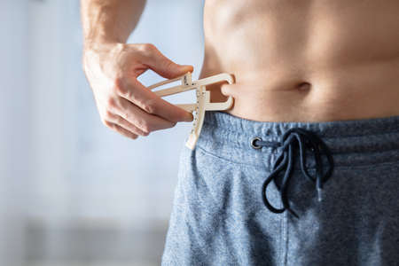 Close-up Of A Athlete Person Measuring His Body Fat With Caliper In The Gymの写真素材