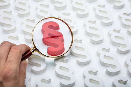 Close-up Of A Person Looking At Red Paragraph Symbol Through Magnifying Glassの写真素材