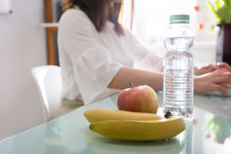 Banana And Water Bottle On Reflective Deskの写真素材