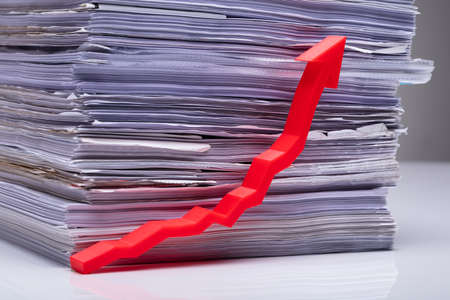 Red Increasing Growth Arrow In Front Of Stacked Document On Reflecting Tableの写真素材