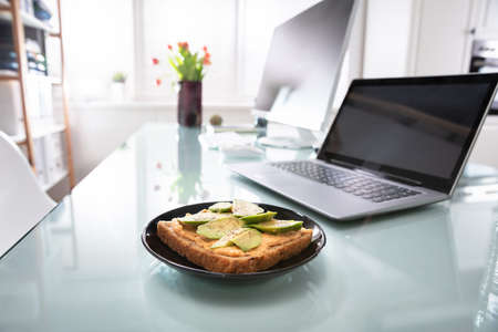 Healthy Sandwich In Plate Near Laptop Over Reflective Deskの写真素材