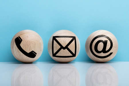 Three Wooden Ball With Contact Icon Arranging In A Row Over Reflecting Floorの写真素材