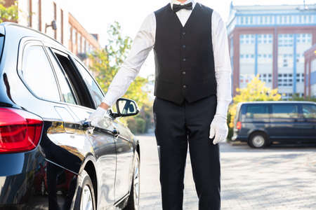 Valet's Hand Opening Black Car Door On Streetの写真素材