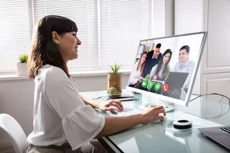 Businesswoman Videoconferencing With Her Colleagues On Computer At Workplace