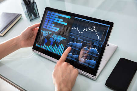 Close-up Of A Businesswoman's Hand Analyzing Graph On Digital Laptop At Workplace