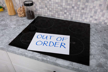 Written Text Out Of Order Message On Paper Over The Stuck Induction Stove In Kitchen