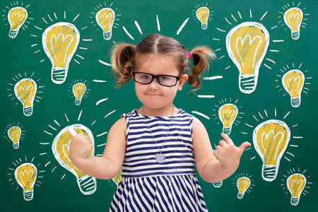 Smiling Pretty Girl Pointing To Words The Idea Icons Standing In Front Of Chalkboardの写真素材