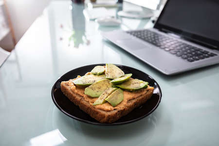 Healthy Sandwich In Plate Near Laptop Over Reflective Desk